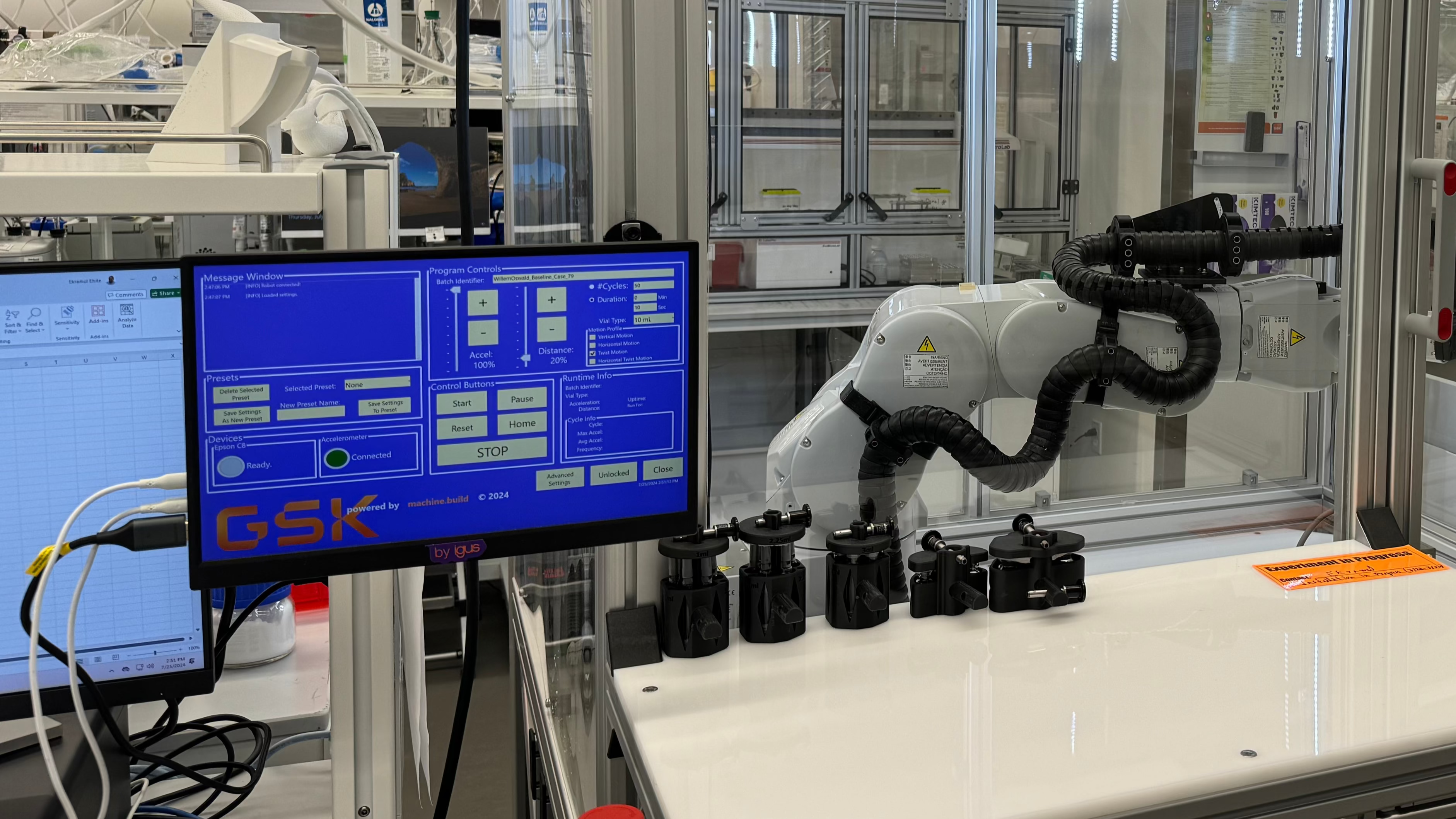 Robot arm in a laboratory setting with  custom EOAT and a computer monitor displaying HMI software interface.